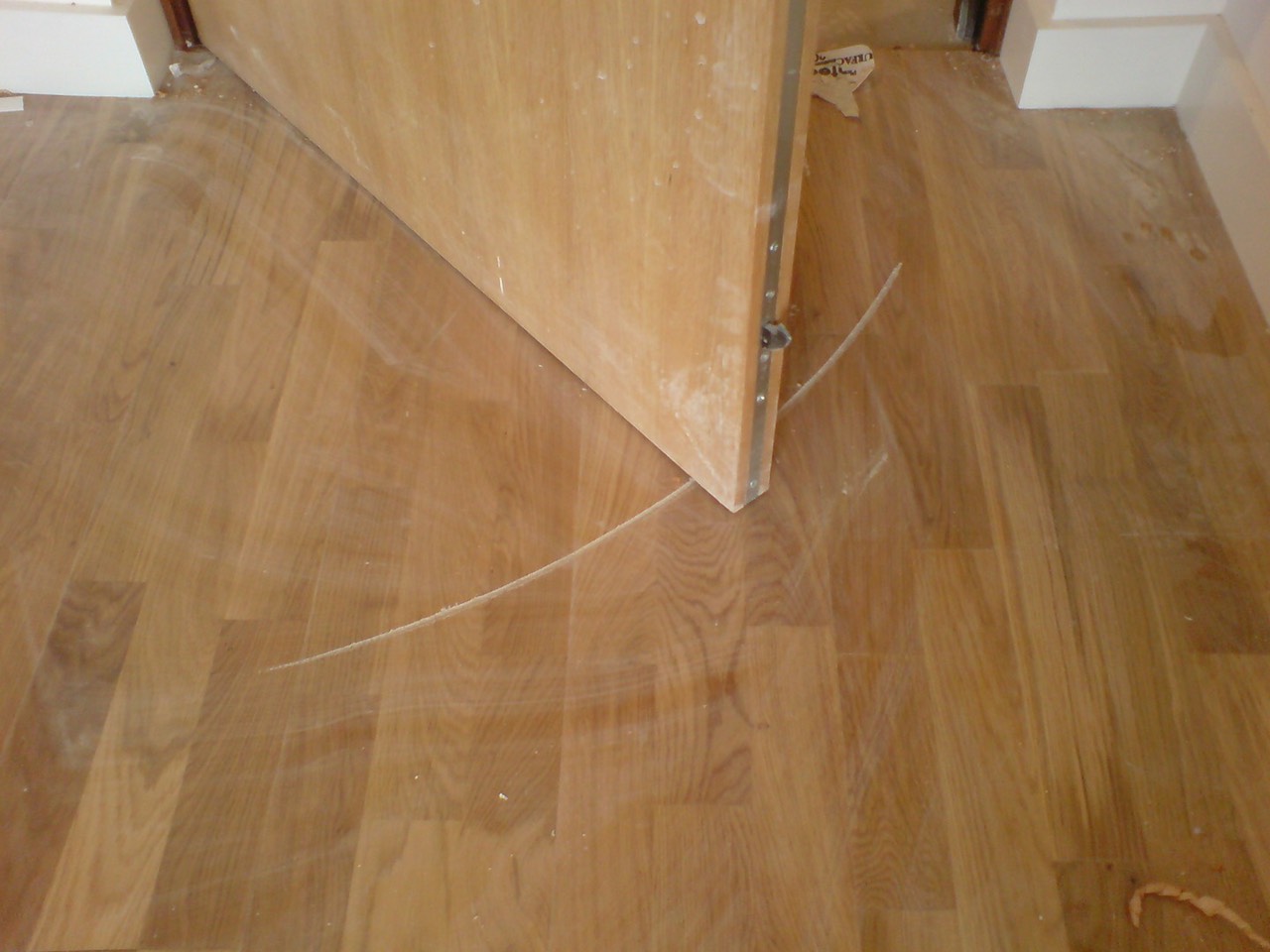 Cạnh cửa với bề mặt sắc nhọn tạo vết xước trên bề mặt sàn gỗ.